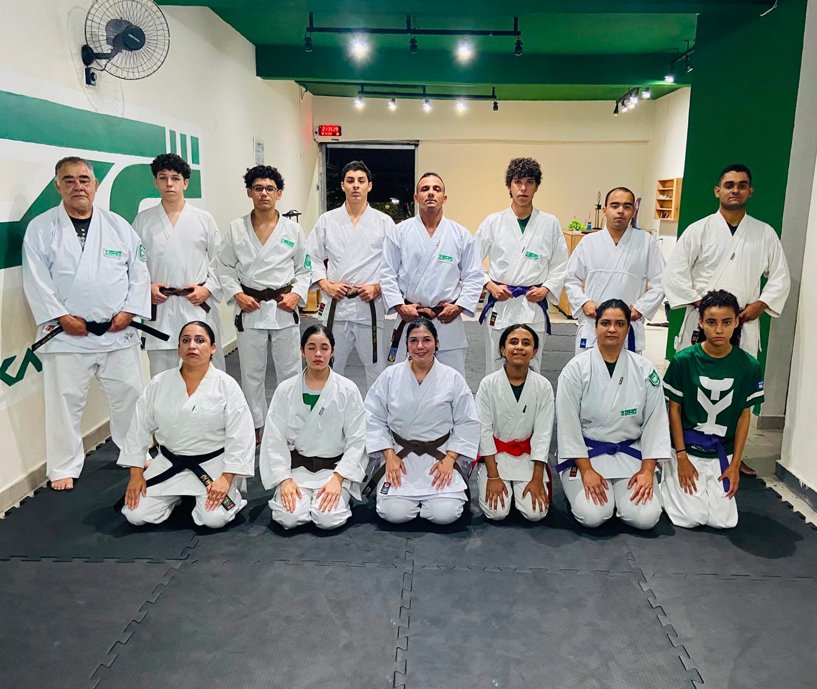 Filosofia na EKG: foto da equipe de karatê reunida em duas fileiras, adultos e jovens de kimono branco com faixas de diferentes graduações.